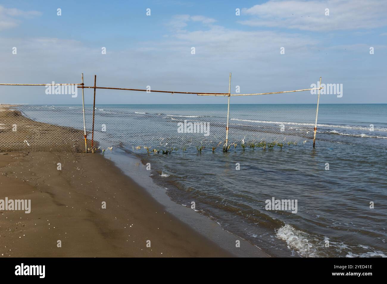 Maschendrahtzaun an einem Sandstrand. Ein Zaun blockiert den Zugang zum Strand. Kaspisches Meer, Iran Stockfoto