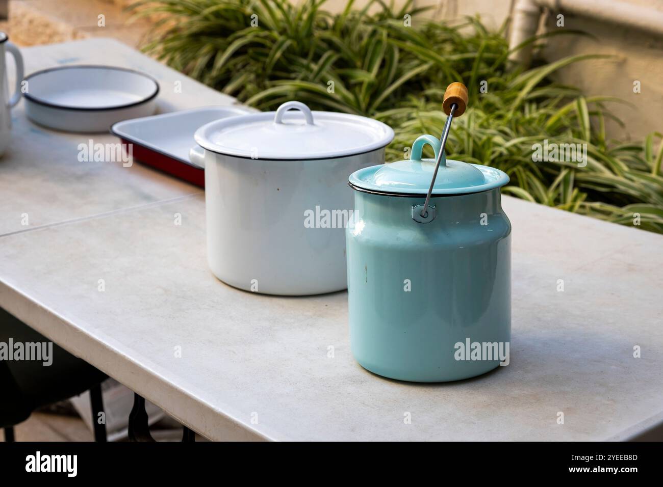 Vintage Emaille Milchkannen, einschließlich einer blauen und Teller auf einem Tisch am Eingang als Dekoration. Stockfoto