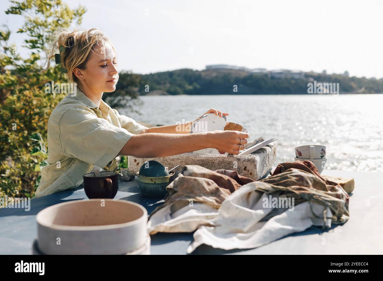 Handwerkerin, die Keramikbecher im Sonnenlicht auf dem Tisch trocknet Stockfoto