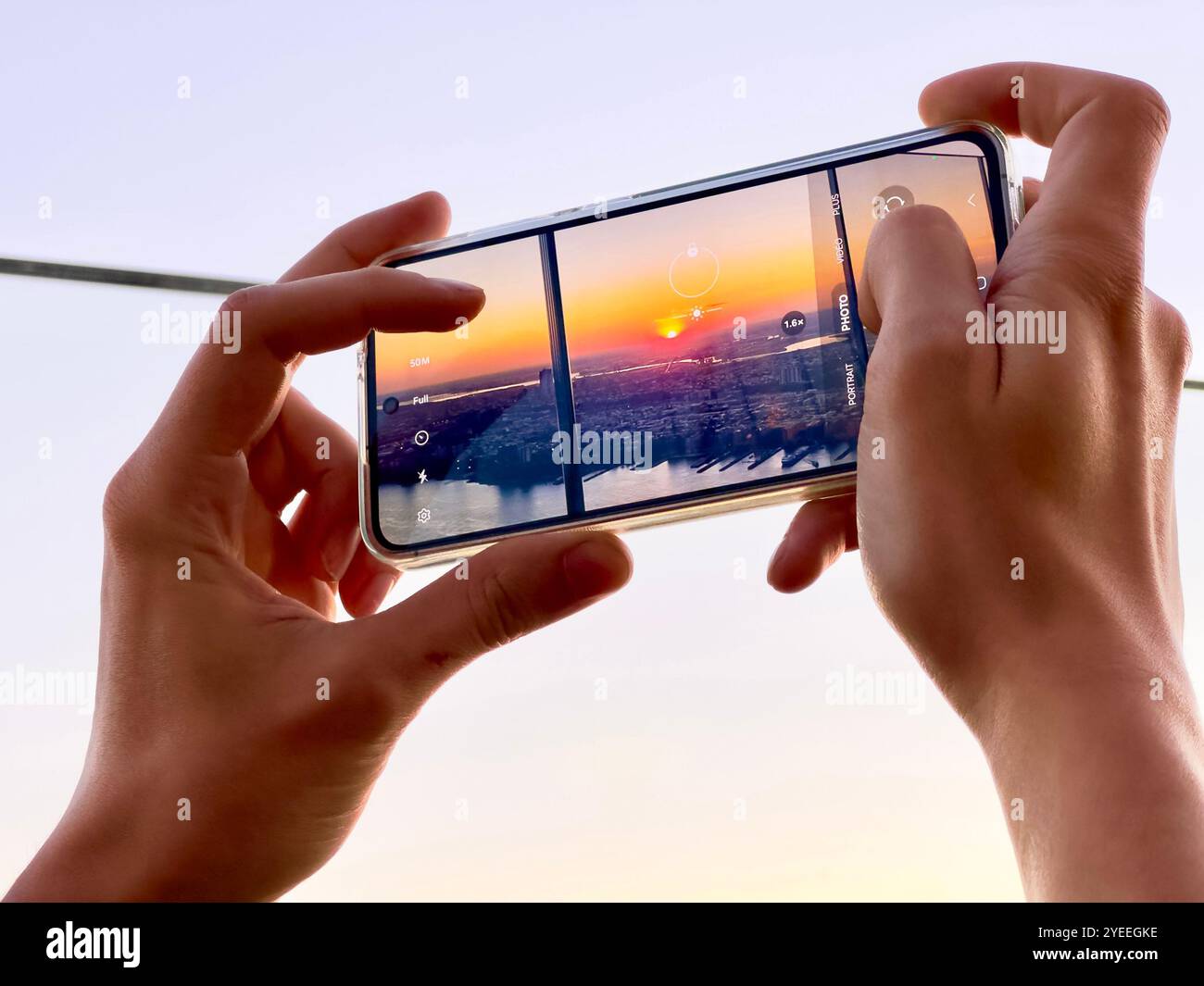 Hände einer Person, die ein Smartphone benutzt, um einen Sonnenuntergang von manhattan New york City von der Aussichtsplattform des Randes hudson Yards nyc aufzunehmen - Smartphone-aufgenommenes Stockfoto