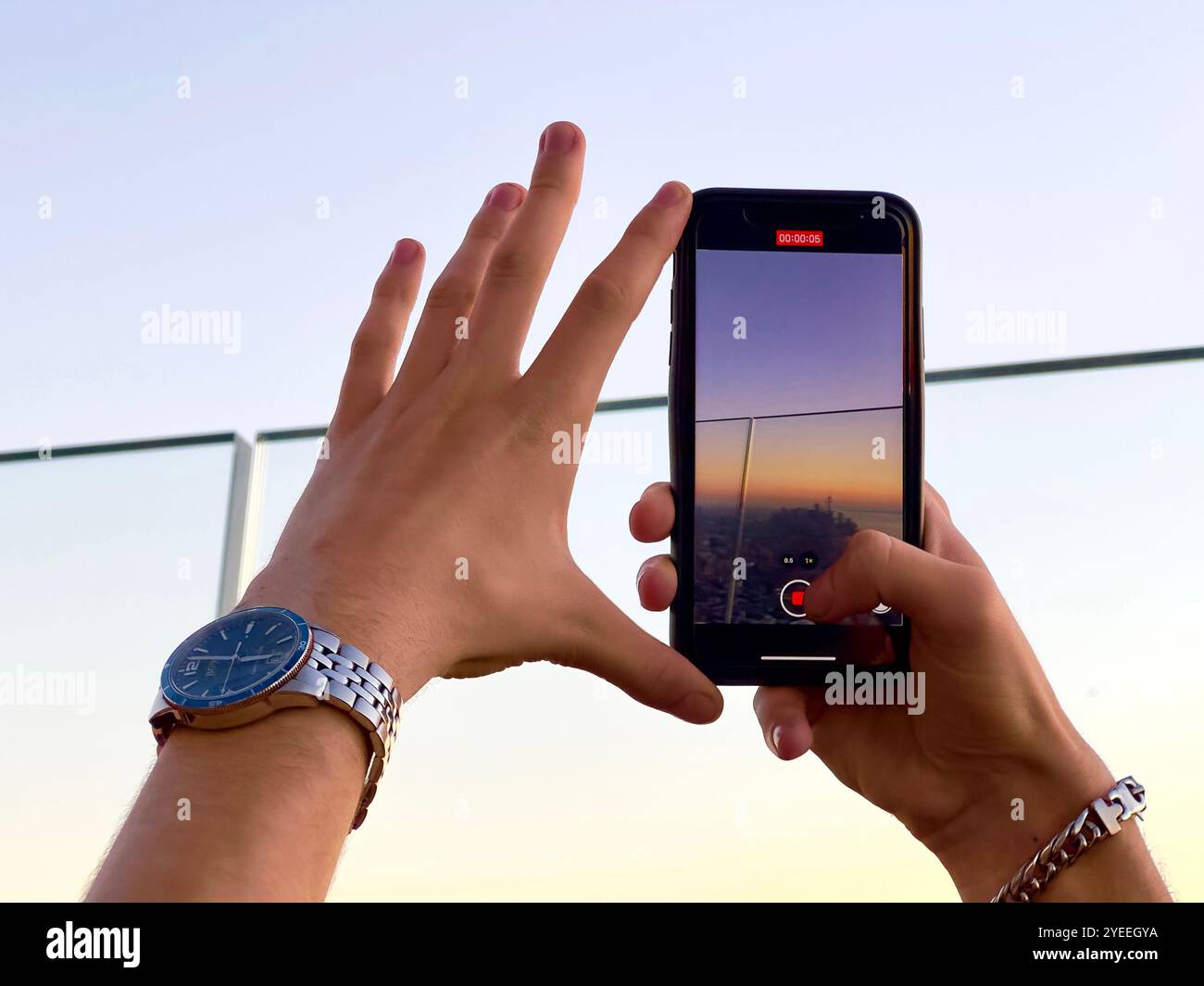 Hände einer Person, die ein Smartphone benutzt, um einen Sonnenuntergang von manhattan New york City von der Aussichtsplattform des Randes hudson Yards nyc aufzunehmen Stockfoto
