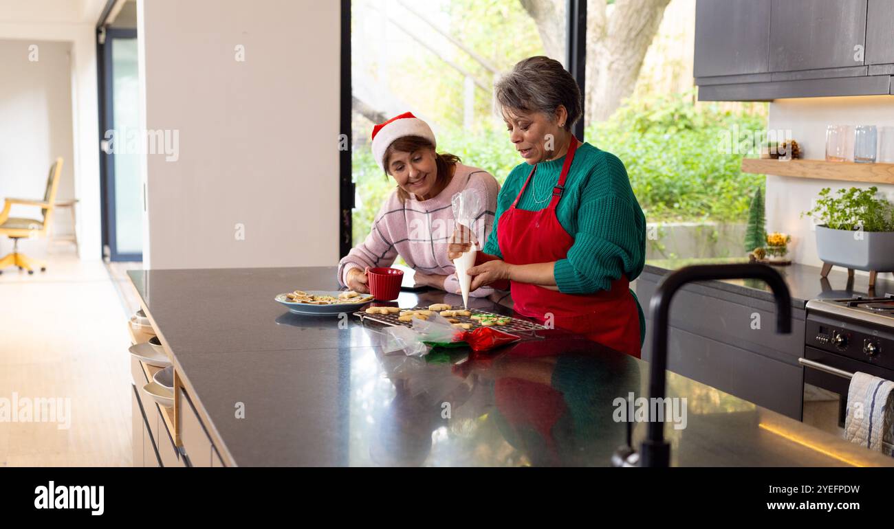 weihnachtskekse dekorieren, ältere Freundinnen in der modernen Küche, zu Hause Stockfoto