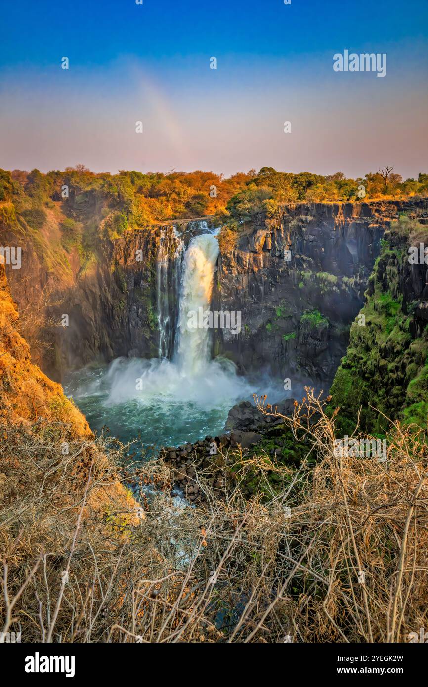 Ein atemberaubender Wasserfall fällt in einen Pool unter einem lebendigen Himmel und zeigt die raue und kraftvolle Schönheit der Natur in lebendigen Farben. Stockfoto