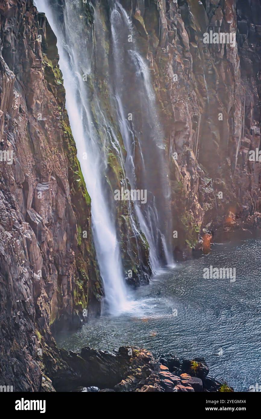 Der mächtige Wasserfall stürzt in einen ruhigen Pool und schafft ein harmonisches Gleichgewicht zwischen dem intensiven Wasserfluss und der friedlichen Umgebung in Sambia Stockfoto
