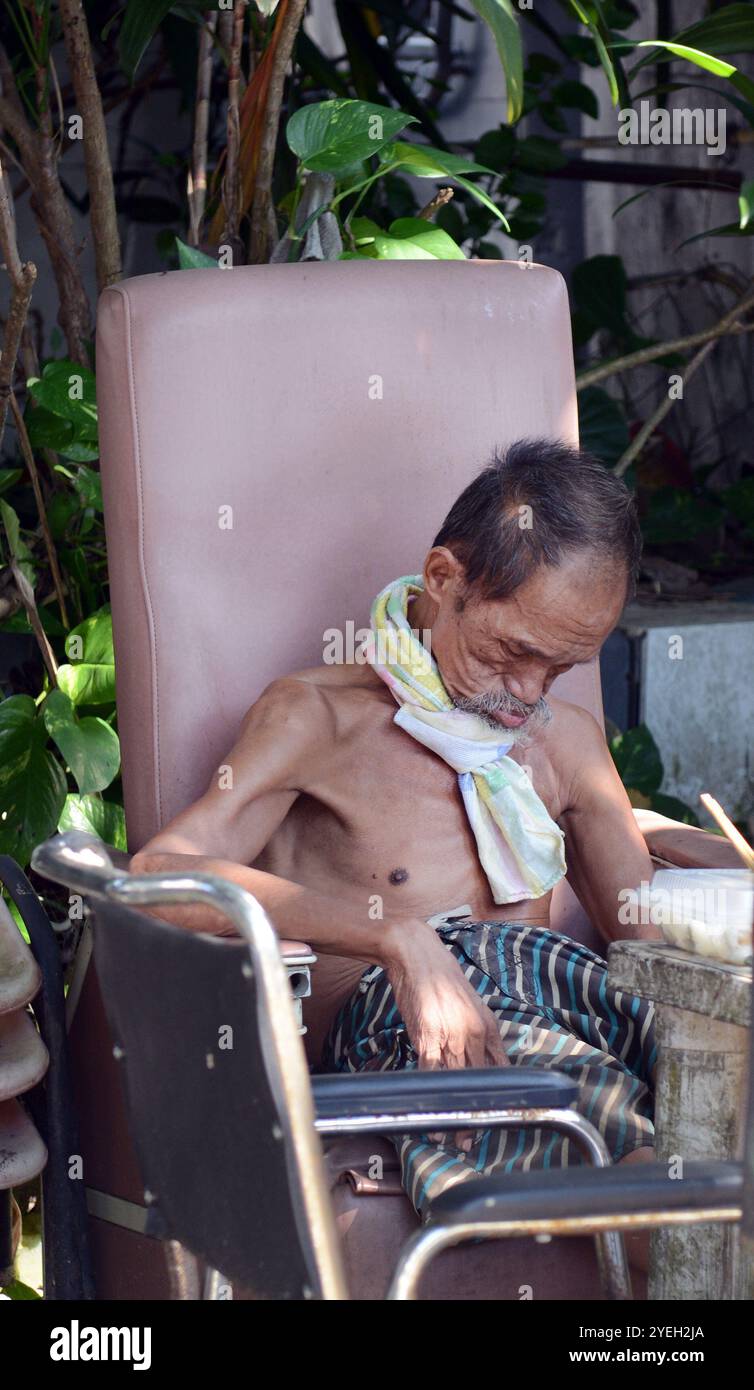 Ein älterer Mann, der ein Nickerchen im Dorf Tai O, Lantau, Hongkong macht. Stockfoto