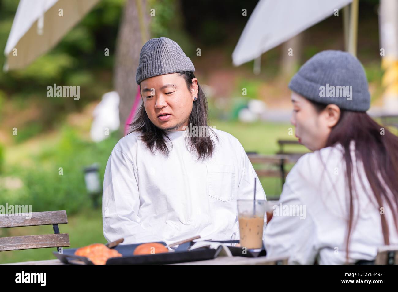 Ein koreanischer Mann und eine Japanerin, beide im Alter von 30 Jahren und ein verheiratetes Paar, genießen in einem stilvollen Café im Herbst einen Brunch mit drei Hunden Stockfoto