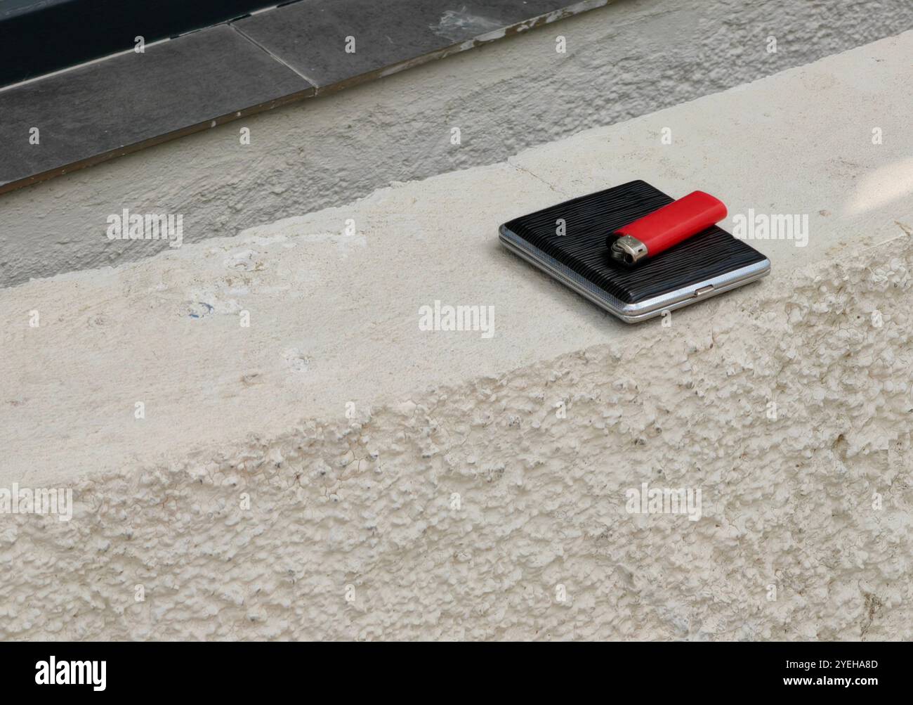 Black Tobacco Snuff Box und Red Feuerzeug auf Beton – Rauchgewohnheitskonzept Stockfoto