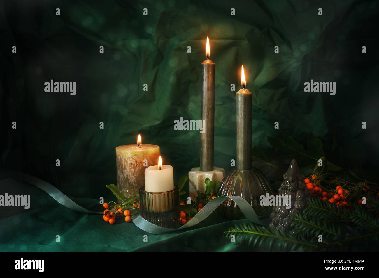 Vierter Advent mit vier beleuchteten Kerzen, Tannenzweigen, roten Orangenbeeren und Weihnachtsdekoration, dunklem und stimmungsvollem grünem Hintergrund, Weihnachtskonzept, Kopie sp Stockfoto
