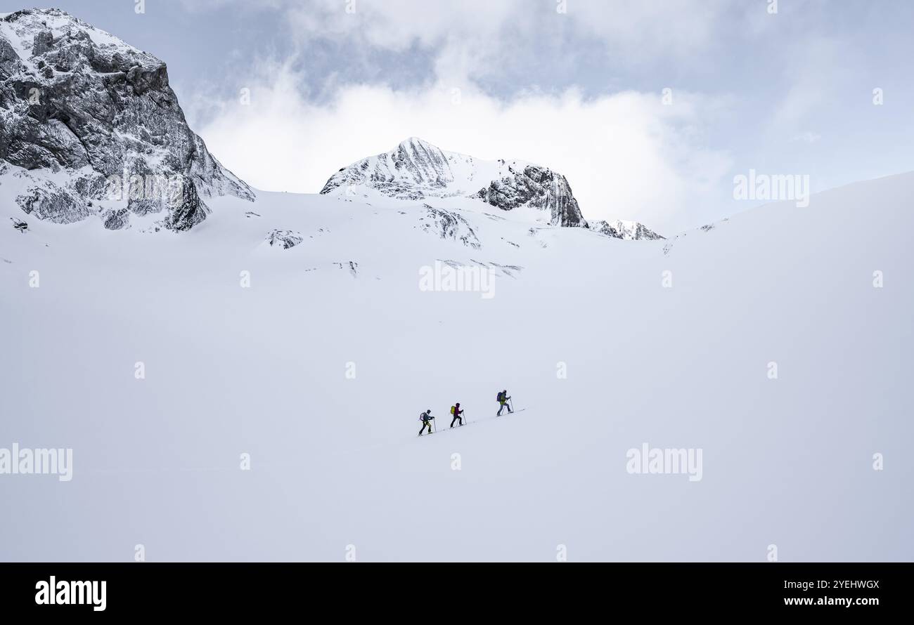 Drei Skitourenfahrer in einsamer Landschaft, verschneite Berglandschaft, bewölkte Stimmung, hohe Tour, Berner Alpen, Bernese Oberland, Schweiz, Europa Stockfoto