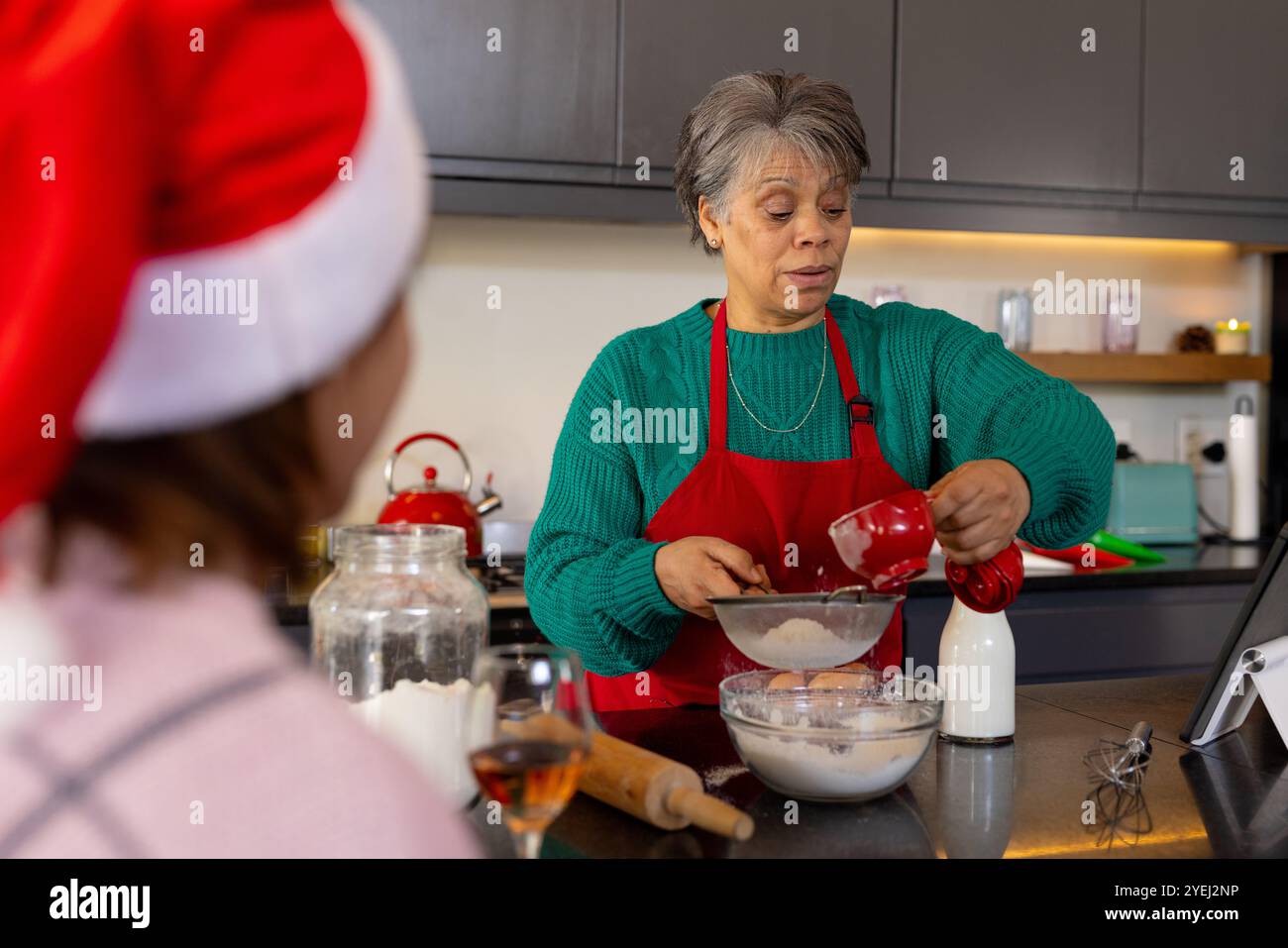 Seniorin, die in der Küche backen, Schürze tragen, Weihnachtsgeschenke zubereiten, zu Hause Stockfoto