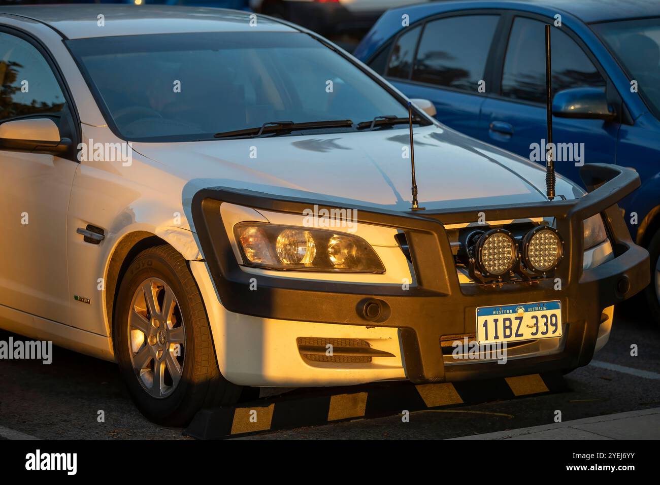 Eine weiße Holden-Limousine mit einer großen Bullenstange an der Vorderseite, ausgestattet mit Spots und zwei Radioantennen, die während des Sonnenuntergangs auf einem Parkplatz geparkt wurde. Stockfoto