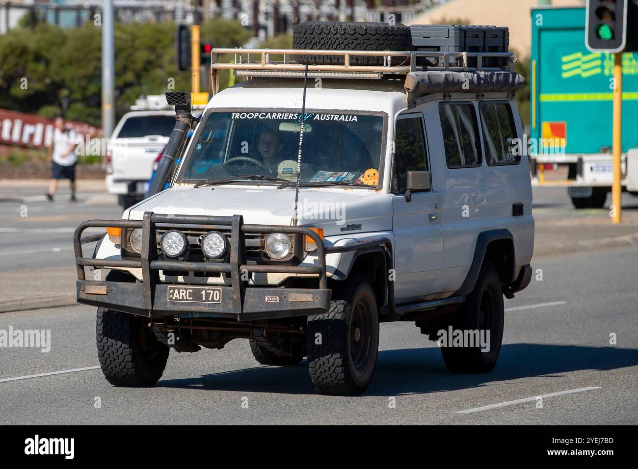 Das Bild zeigt einen weißen Toyota Land Cruiser Truppenträger (oft als „Troopy“ bezeichnet), der eine Stadtstraße hinunterfährt. Stockfoto