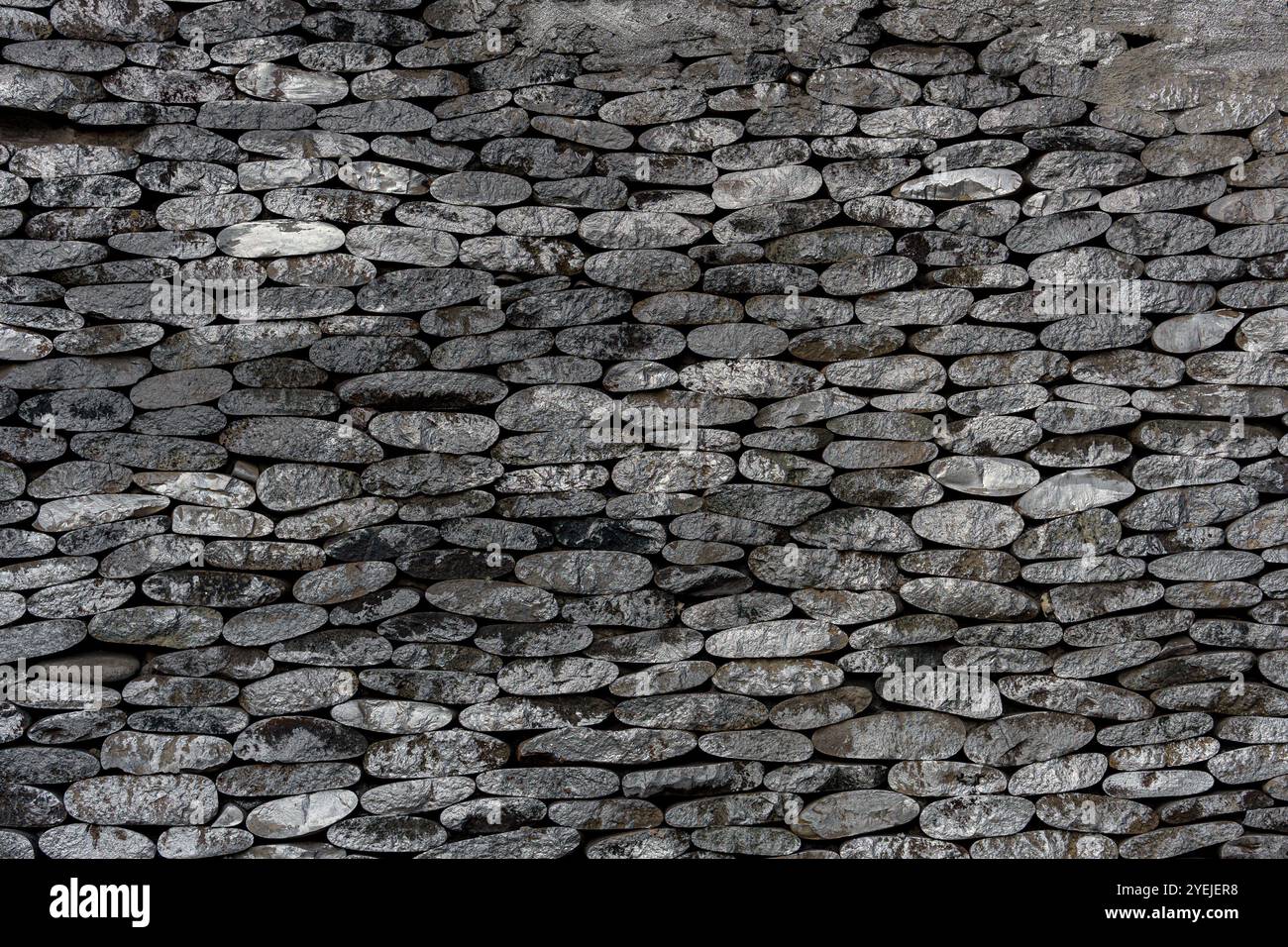 Steinwand aus gestapelten flachen Steinen, horizontal angeordnet. Die Steine passen eng aneinander. Stockfoto