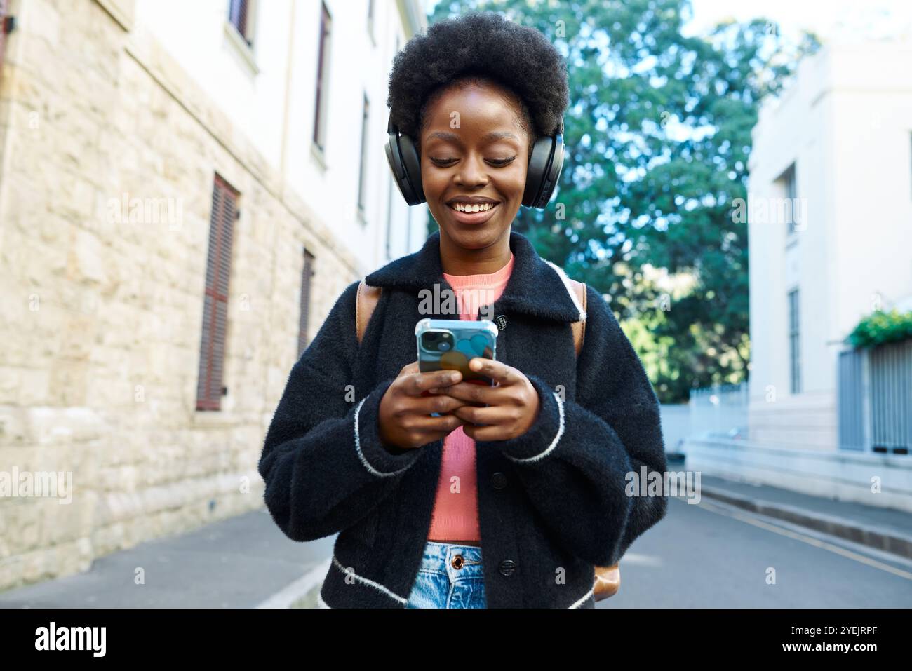 Junge Frau, die Musik am Telefon genießt, während sie in städtischer Umgebung läuft Stockfoto