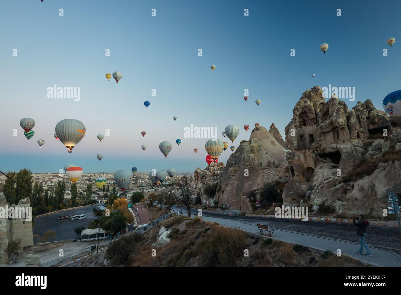 Farbenfrohe Heißluftballons erheben sich anmutig über die einzigartigen Felsformationen Kappadokiens, wenn die Dämmerung bricht Stockfoto