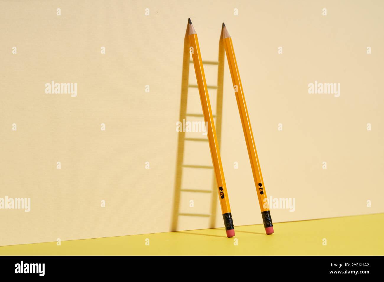 Zwei Bleistifte auf dem Schreibtisch werfen einen Schatten der Leiter - Erfolg durch Bildung Stockfoto