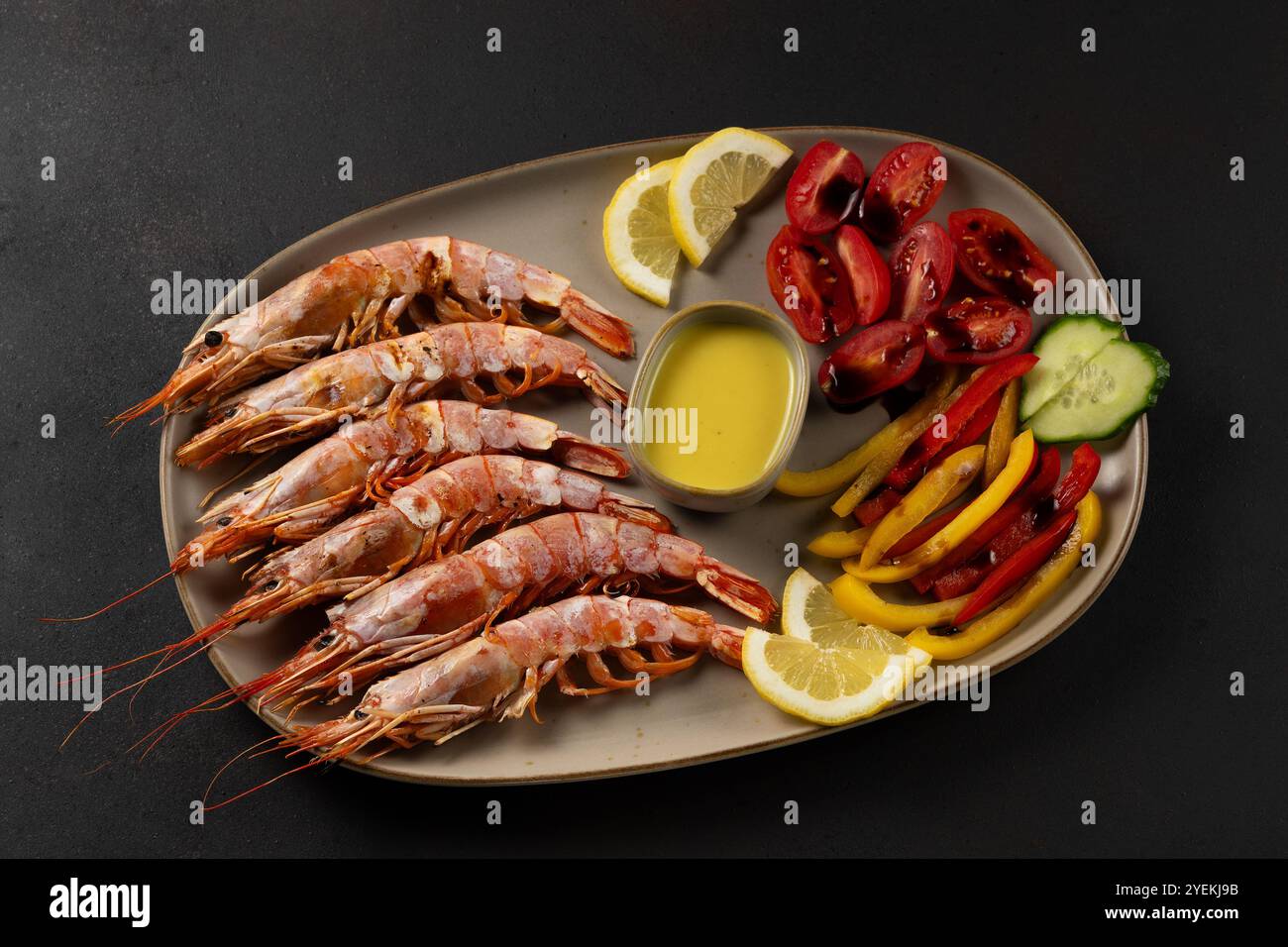 Gebratene Garnelen auf Teller mit frischem Gemüse und Zitronenscheibe. Meeresfrüchte im Hintergrund. Stockfoto