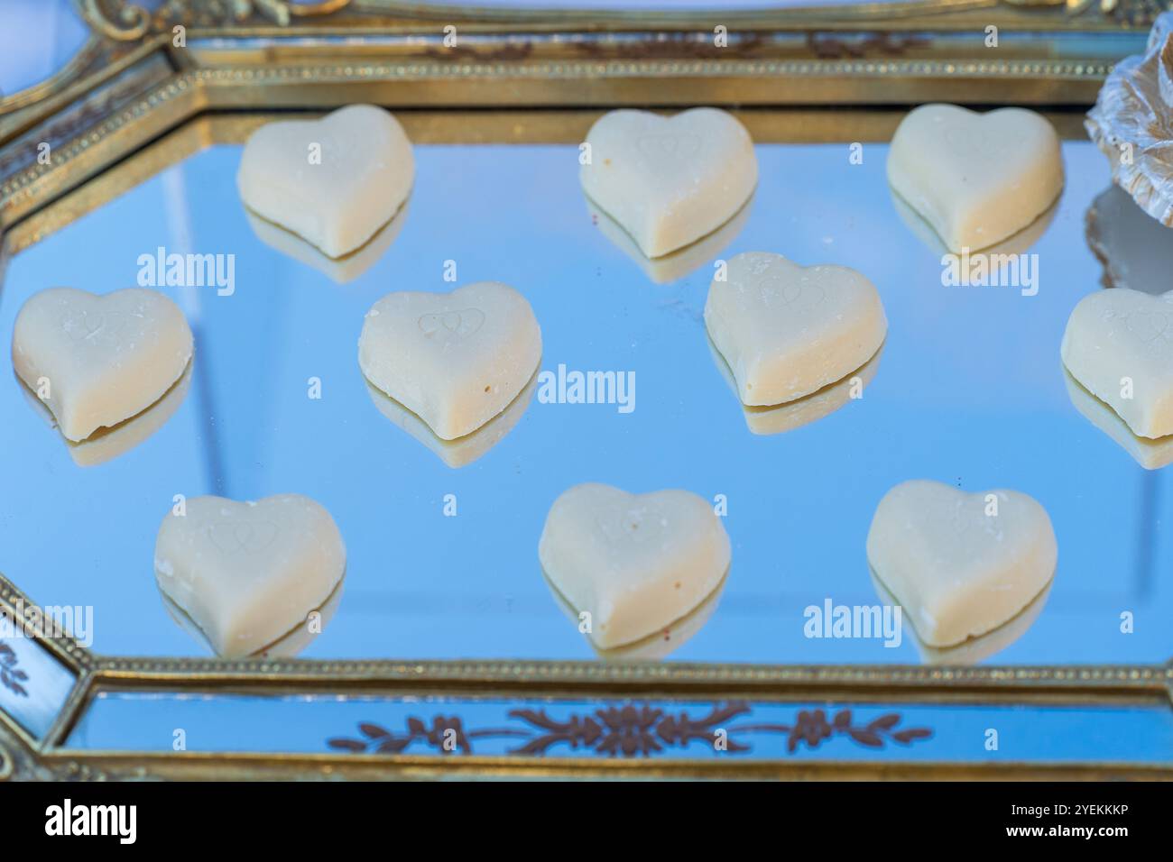 Weiße Herzsüße auf reflektierendem Tablett – Liebe ist überall. Hochzeitskonzept Stockfoto