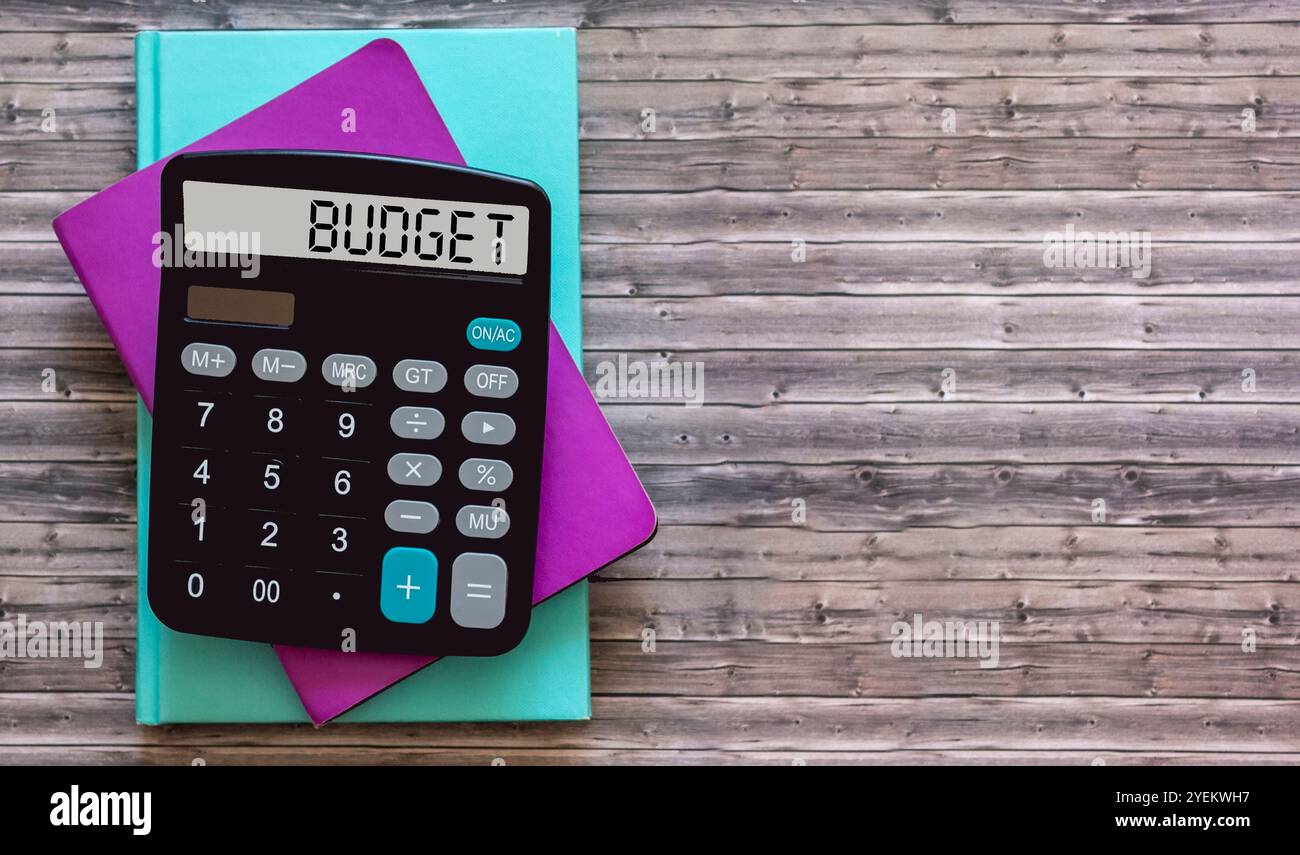 Das Wort Budget auf dem Taschenrechnerdisplay, auf einem Holztisch mit Notizbüchern Stockfoto