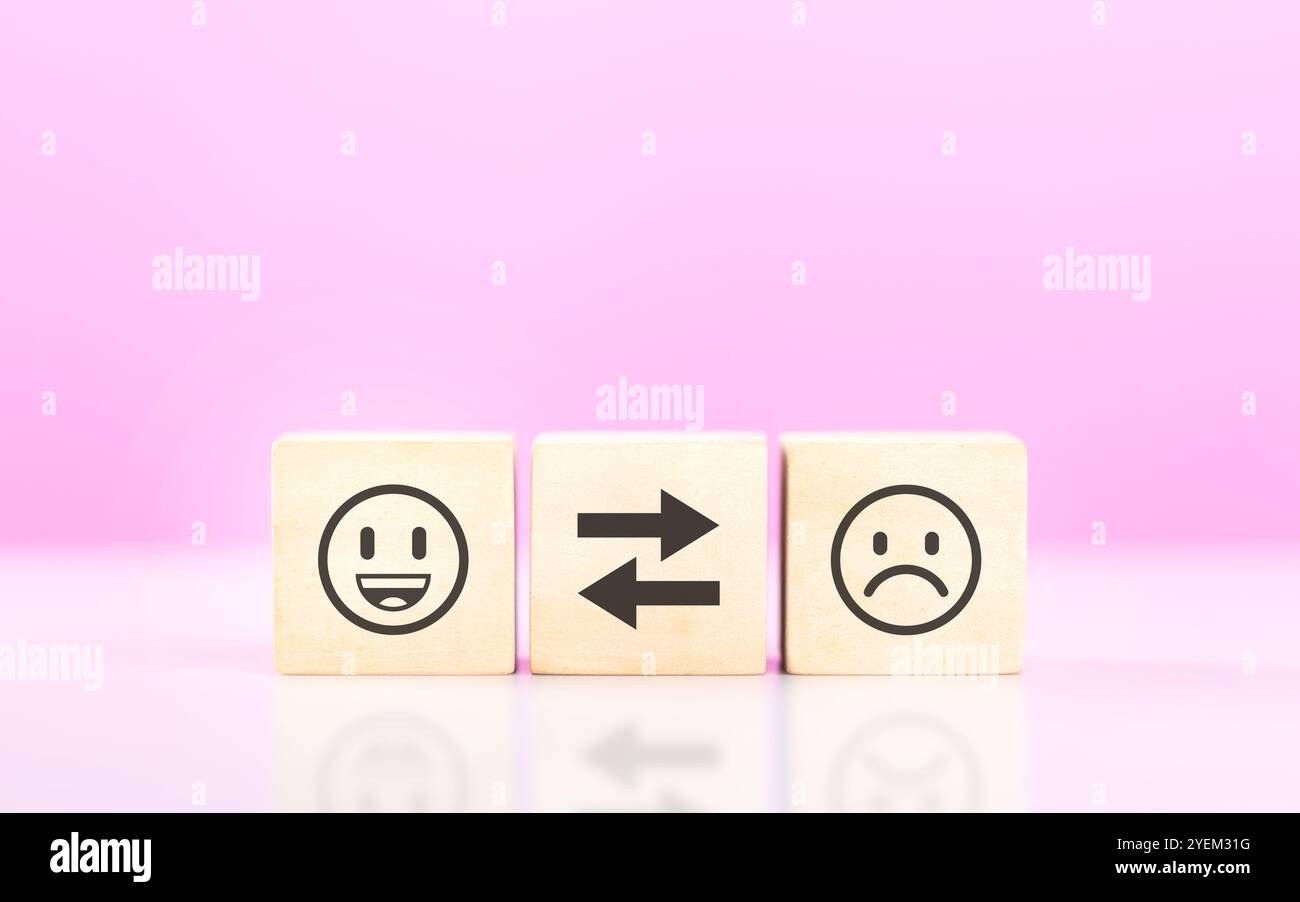 Holzblöcke mit Smiley- und traurigen Gesichts-Aufklebern symbolisieren das Konzept, zwischen Glück und Traurigkeit zu wählen. Das Bild spiegelt das Emotio wider Stockfoto
