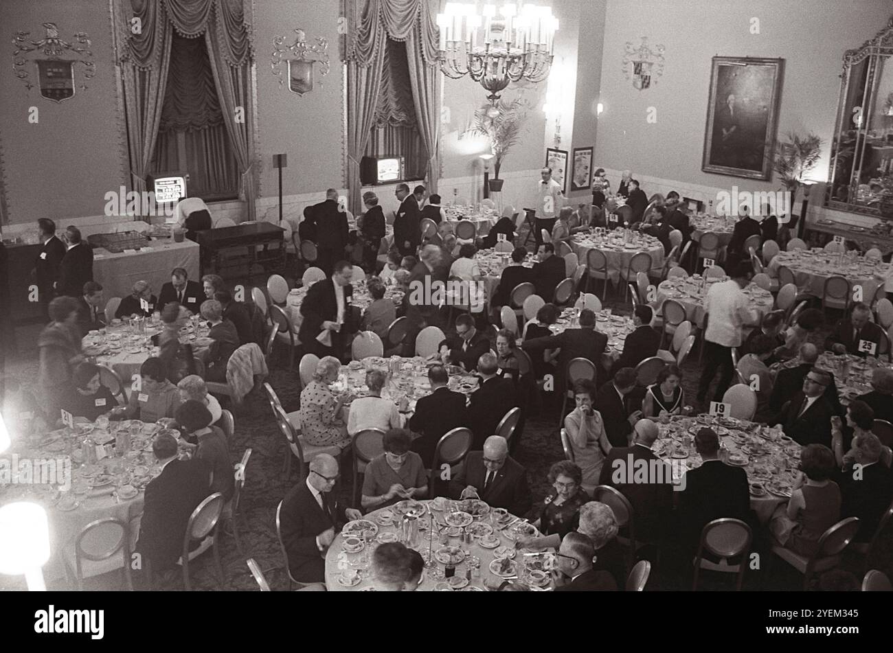 Demokraten saßen an runden Tischen während eines Abendessens im Demokratischen Hauptquartier im Mayflower Hotel, Washington, D.C. am Wahlabend des 3. November 1964; zwei kleine Fernsehbildschirme vor dem Zimmer Stockfoto