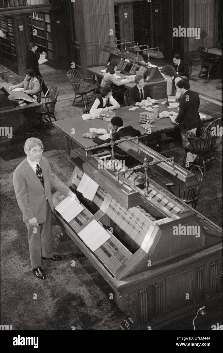 Mann, der neben Gesetzbüchern auf einem Regal steht, und Schirmherren an Tischen in der Supreme Court Library, am United States Supreme Court. USA. 16. Februar 1979 Stockfoto