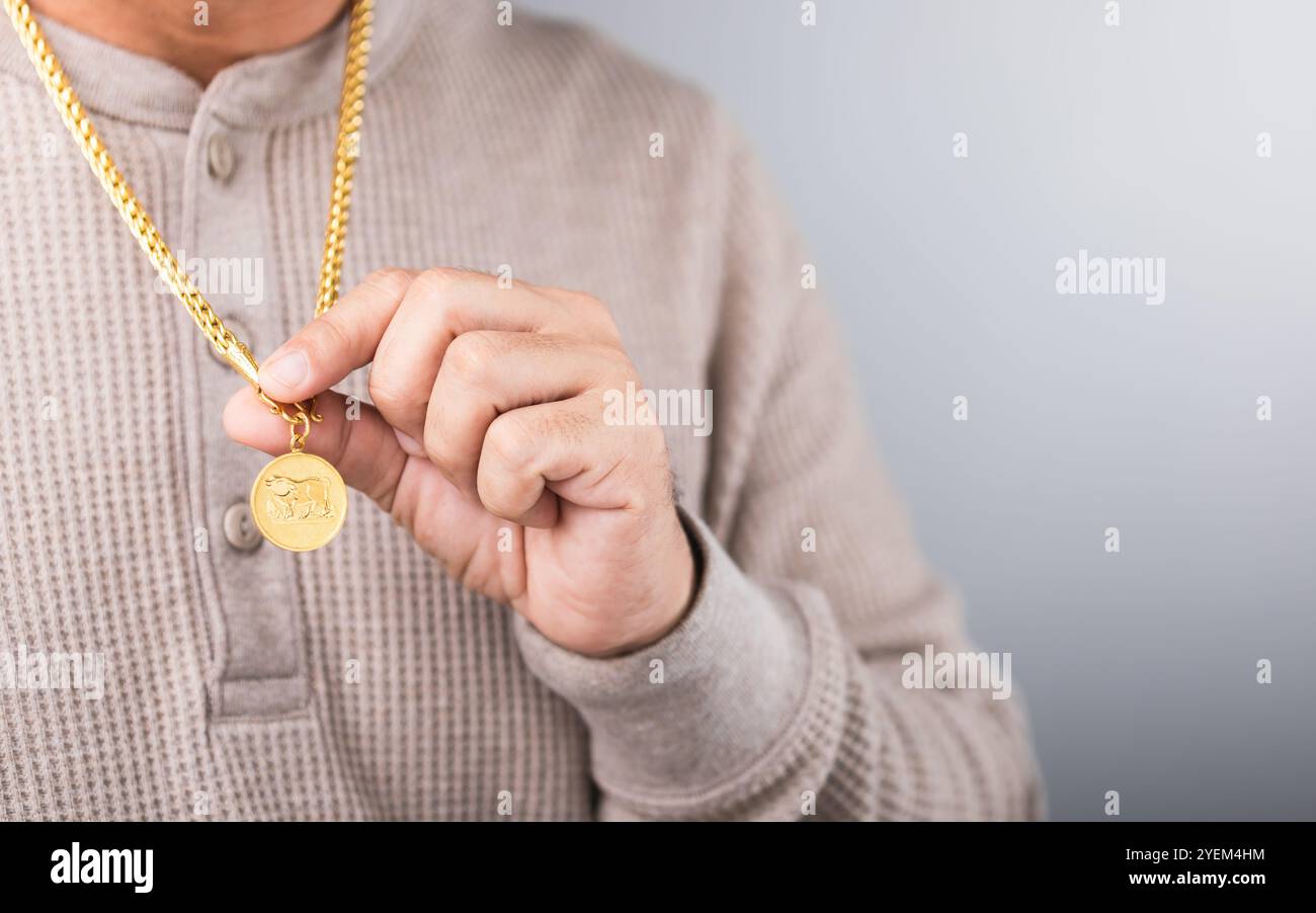 Nahaufnahme eines Mannes, der eine goldene Halskette trägt, symbolisiert Marktspekulation. Stellt das Konzept der Verfolgung der Goldpreise dar und hebt die Verbindung hervor Stockfoto