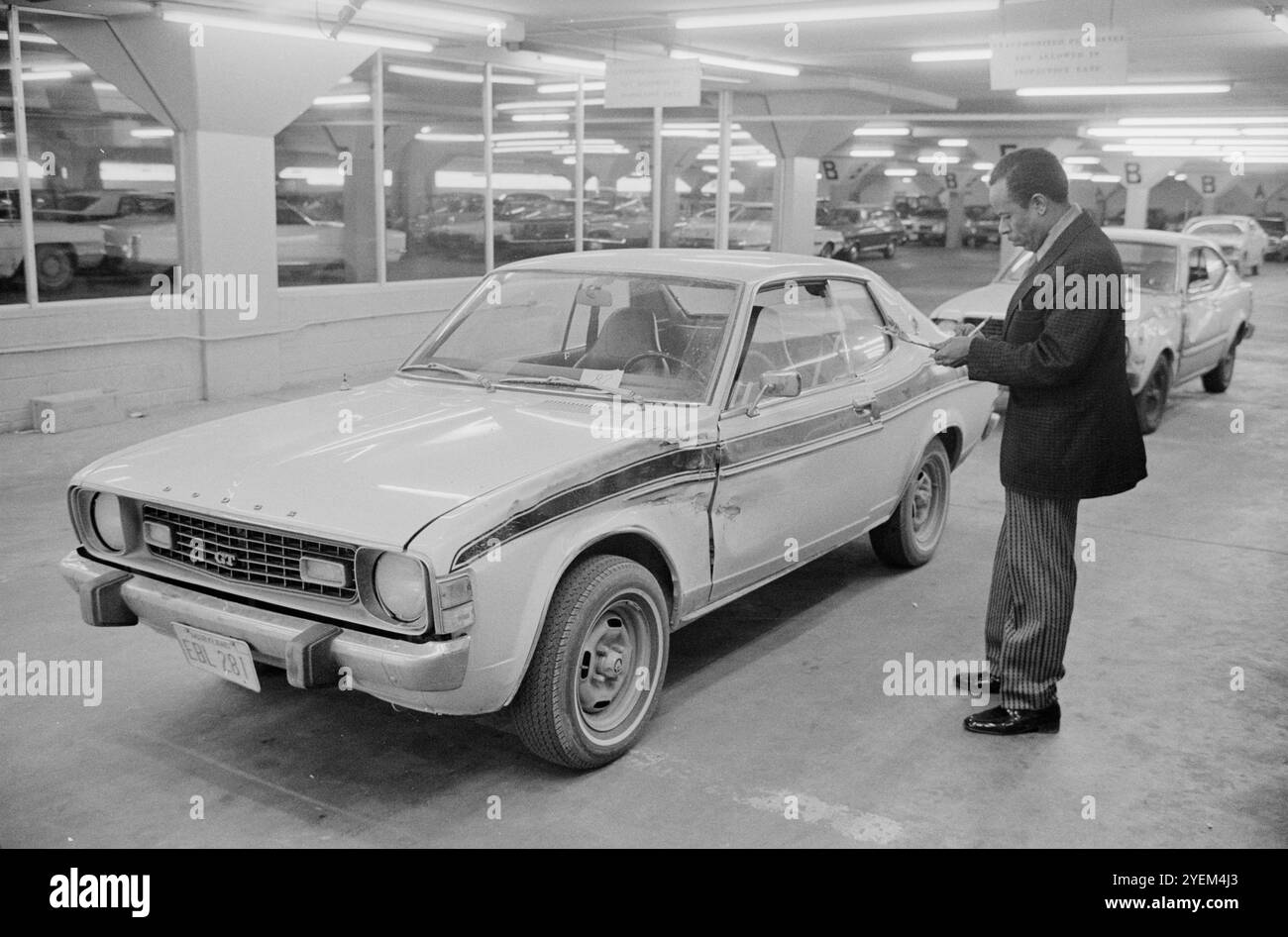 Mann untersucht ein beschädigtes Auto in der Autoschadensschätzung der Government Employees Insurance Company (GEICO). USA. 11. Februar 1976 Stockfoto