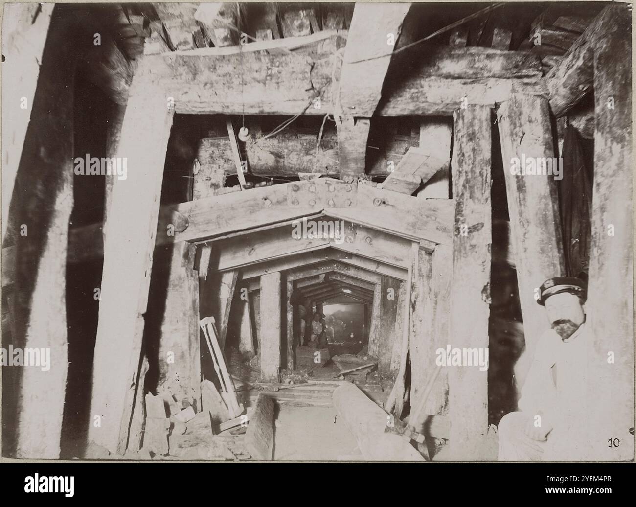 Vintage-Foto von Paris. Metro-Bau in Paris, Firststollen. Frankreich. 1898-1899 unterirdischer Bau (Tunnelbauweise): Aushub von oben nach unten: Zuerst wird der Richttunnel angetrieben, dann wird oben und daneben eine bestimmte Raumlänge für die Krone (Deckengewölbe) ausgegraben und für die Kronenstütze (mit Holz gestützt) ausgegraben. Nach dem Sichern (in der Regel Betonieren) und Entfernen der Zimmerei kann der darunterliegende Gestein stufenweise bis zum gewünschten Raumprofil ausgehoben werden. Blick auf einen Tunnel in instablem Gestein. Der offene Querschnitt, der im Hintergrund sichtbar ist, sollte rou sein Stockfoto
