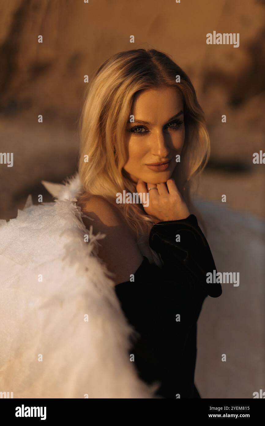 Frau mit Engelsflügeln und dunklen Augen und blondem schwarzem Kleid am Ostseestrand Stockfoto