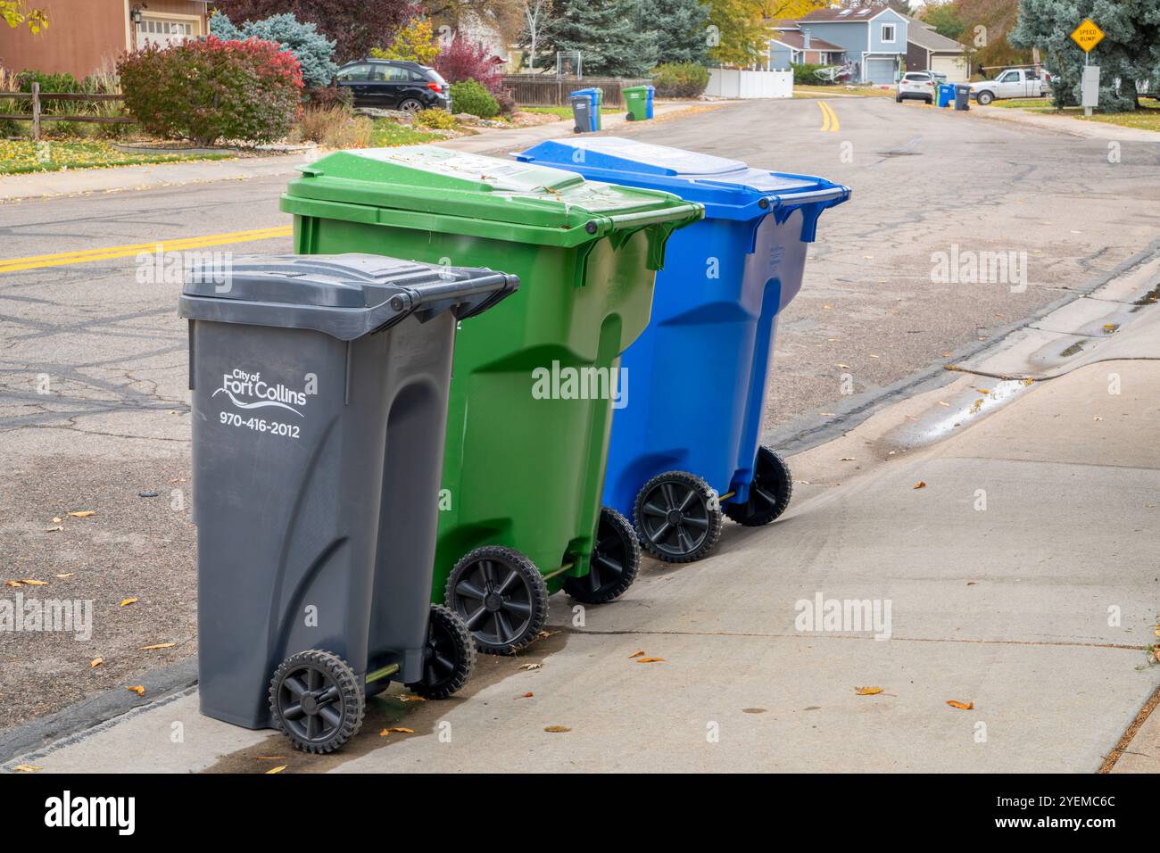 Fort Collins, CO, USA - 30. Oktober 2024: Müllabfuhr - drei Container auf einer Straße für Hausmüll, Gartenabbau und recycelbare Matte Stockfoto