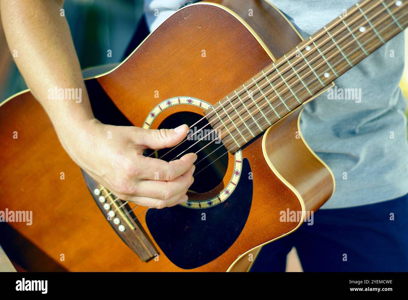 Musikunterricht: Person spielt Akustikgitarre. Kreativität in der Freizeit: сlose-up einer Männerhand, die die Saiten einer klassischen Gitarre zupft. Stockfoto