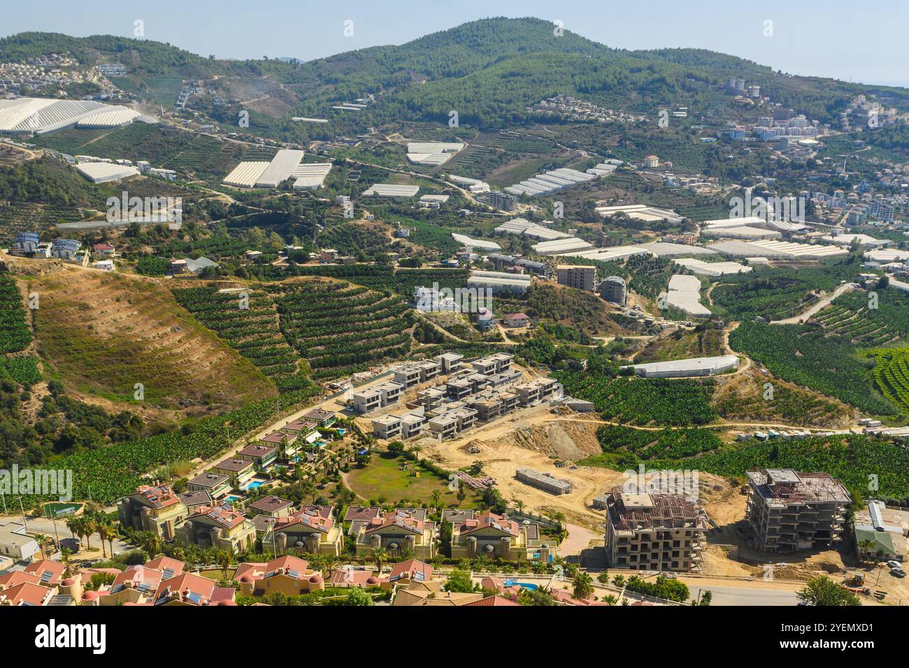 Üppig grüne Hügel sind die Wiege von Terrassenfeldern und modernen Häusern, die eine harmonische Mischung aus Natur und Entwicklung bieten. Stockfoto