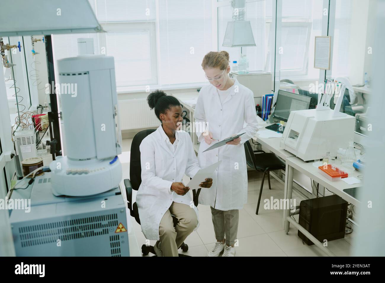 Wissenschaftler arbeiten in Laborumgebungen zusammen, diskutieren Forschungsdaten unter Verwendung fortschrittlicher wissenschaftlicher Geräte, fördern Innovation und Entdeckung in der Wissenschaft Stockfoto