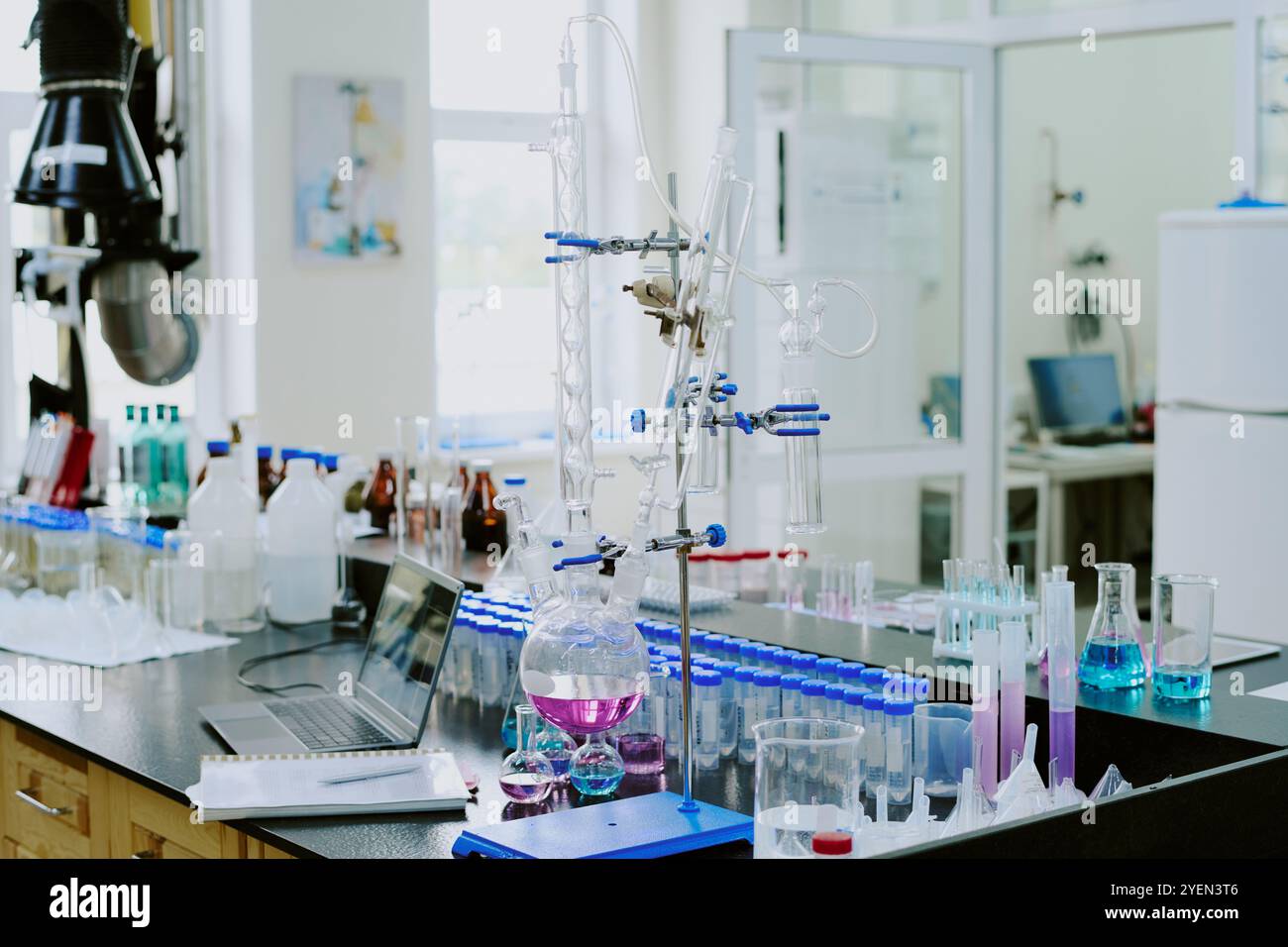 Labor mit modernen Chemiegeräten und verschiedenen Glasapparaten für Experimente mit farbigen Flüssigkeiten, die dem Arbeitsbereich mehr Lebendigkeit verleihen Stockfoto