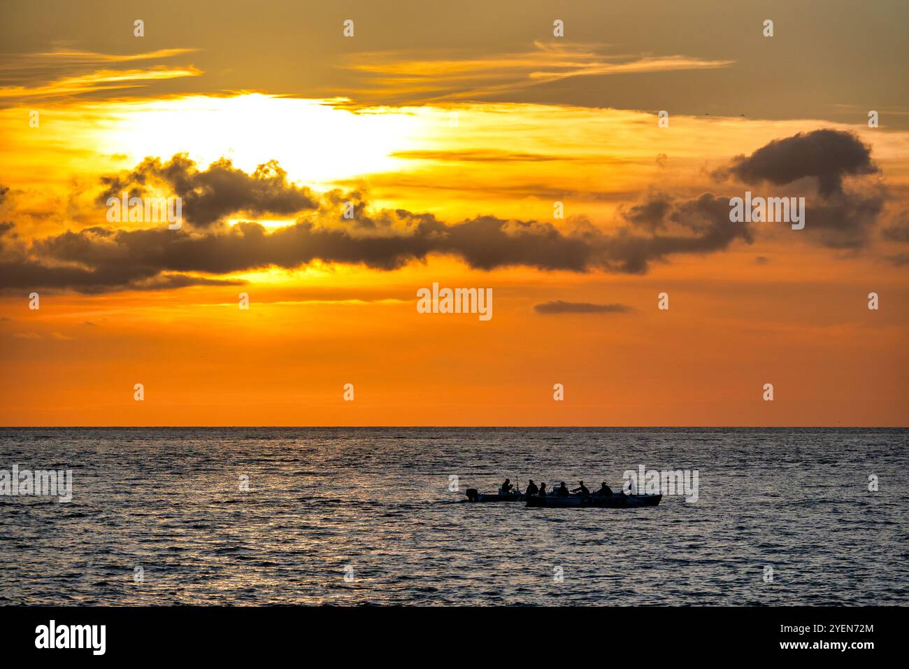 Silhouetten-Ruderteam, das vor der Küste von Livorno, Italien, bei Sonnenuntergang unter einem pulsierenden Himmel trainiert. Stockfoto