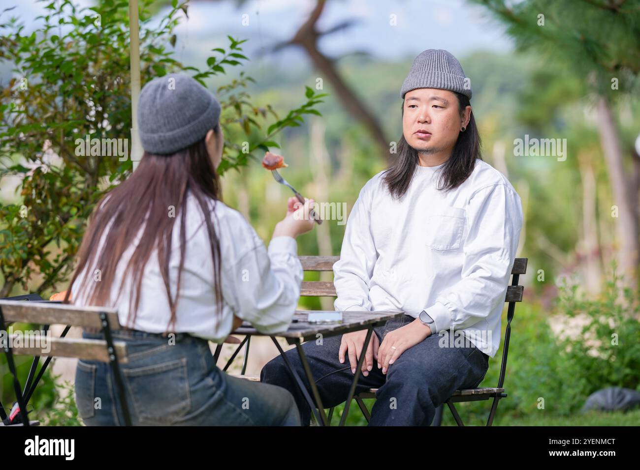 Ein koreanischer Mann und eine Japanerin, beide im Alter von 30 Jahren und ein verheiratetes Paar, genießen in einem stilvollen Café im Herbst einen Brunch mit drei Hunden Stockfoto