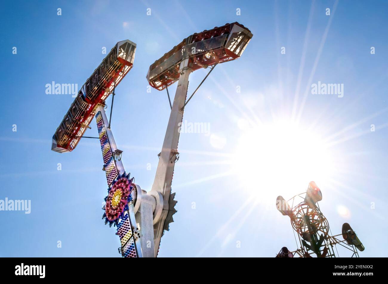 Fotografie einer Fahrt mit dem Vergnügungspark Kamikaze. Das Bild zeigt eine helle und energetische Komposition, die ein Gefühl von Spannung und Bewegung ausstrahlt. Stockfoto