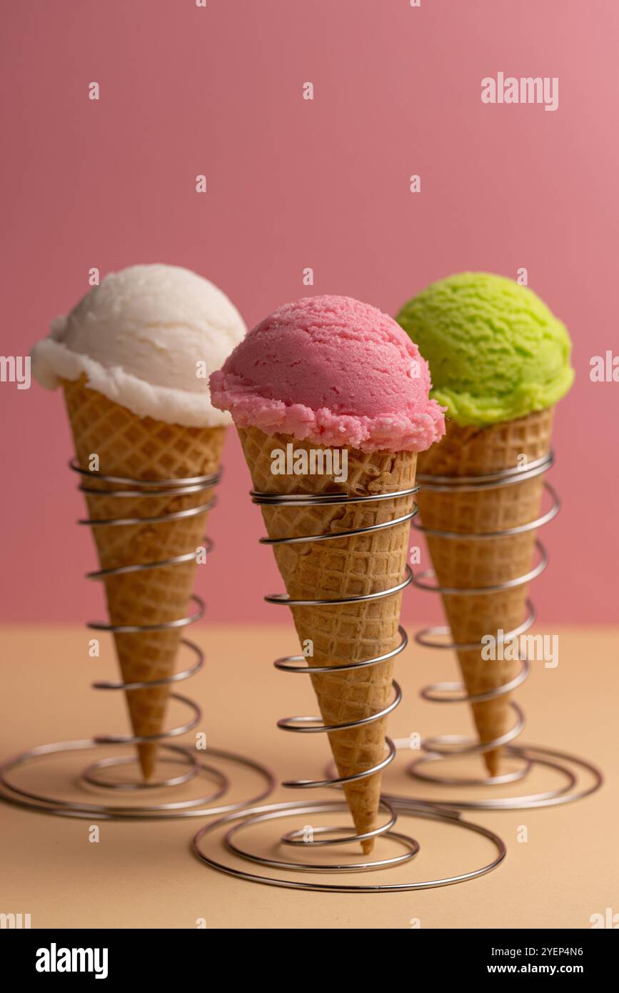 Eine Eiskugel in einem Waffelkegel, eine Auswahl an Aromen, Himbeere, Pistazien, Minze, Erdbeere Stockfoto