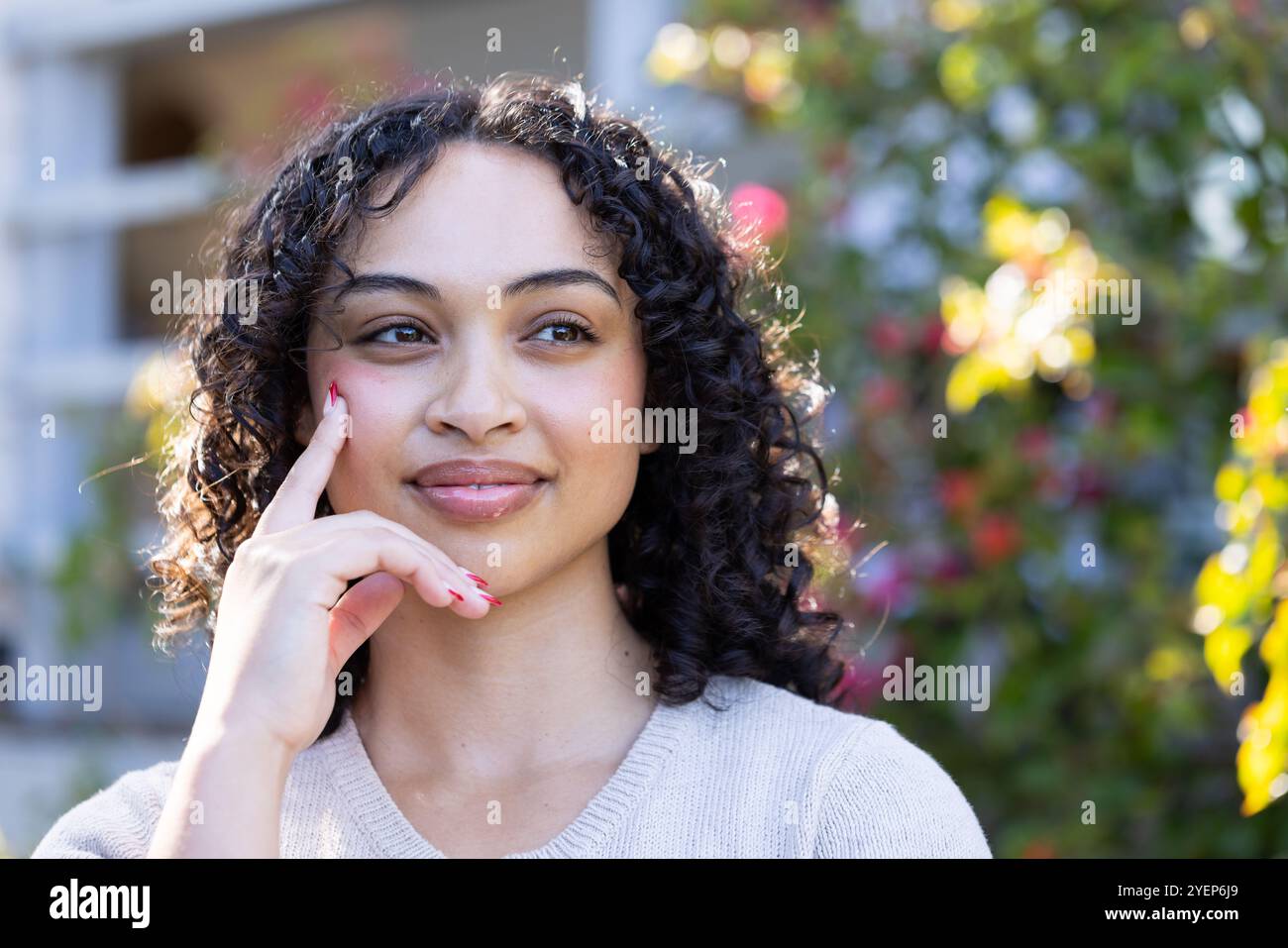Lächelnde Frau genießt einen sonnigen Tag im Garten, fühlt sich nachdenklich und entspannt. Wellness, Entspannung, Natur, Gelassenheit, im Freien, Ruhe Stockfoto