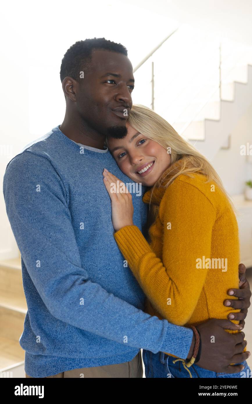 Glückliches, multirassisches Paar, das sich zu Hause umgibt und gemütliche Urlaubsmomente zusammen genießt. Romantik, Liebe, Zuneigung, Zweisamkeit, Glück Stockfoto