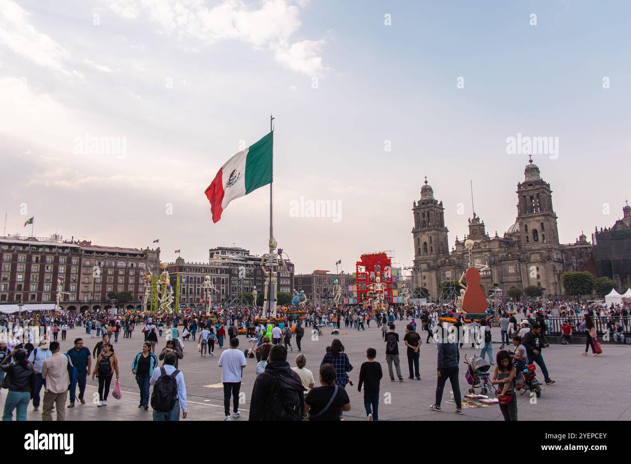 Die große mexikanische Flagge fliegt über Zócalo, umgeben von Dekorationen und Menschenmassen, die den Feiertag feiern. Stockfoto