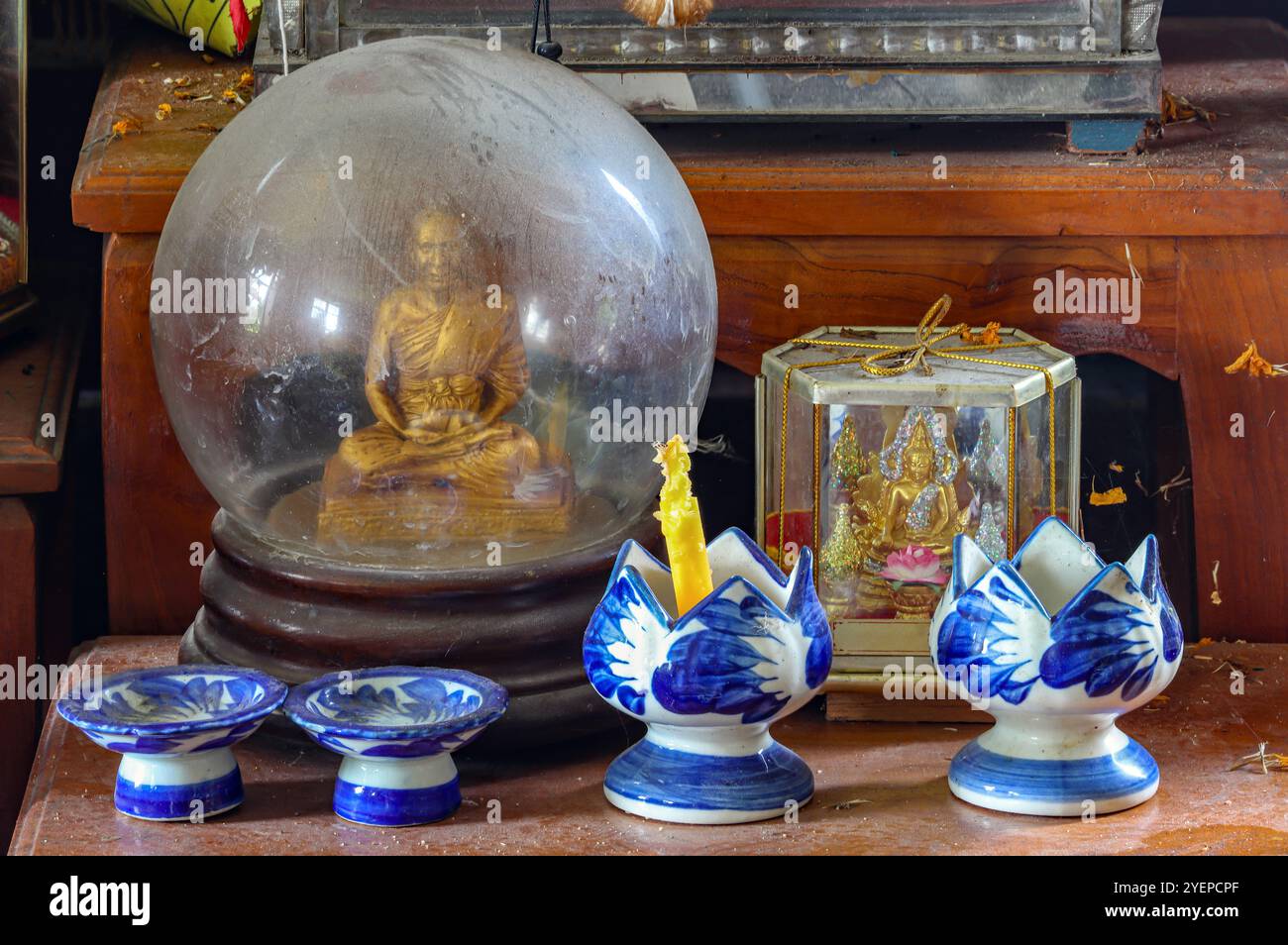 Ein staubiger Hausaltar mit Figuren von Buddha und einem Mönch Stockfoto
