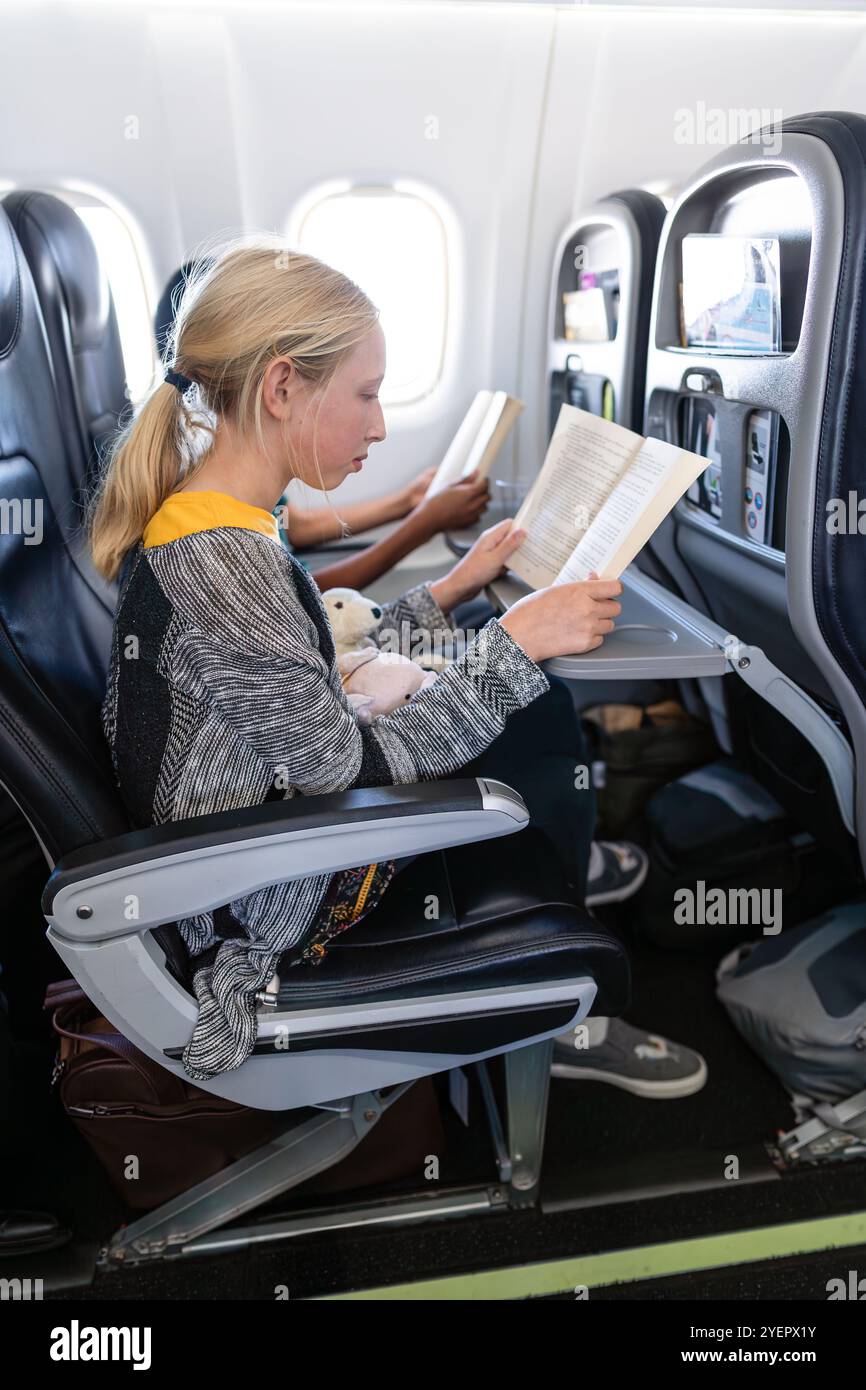 Kind, das im Flugzeug reist, liest Buch Stockfoto