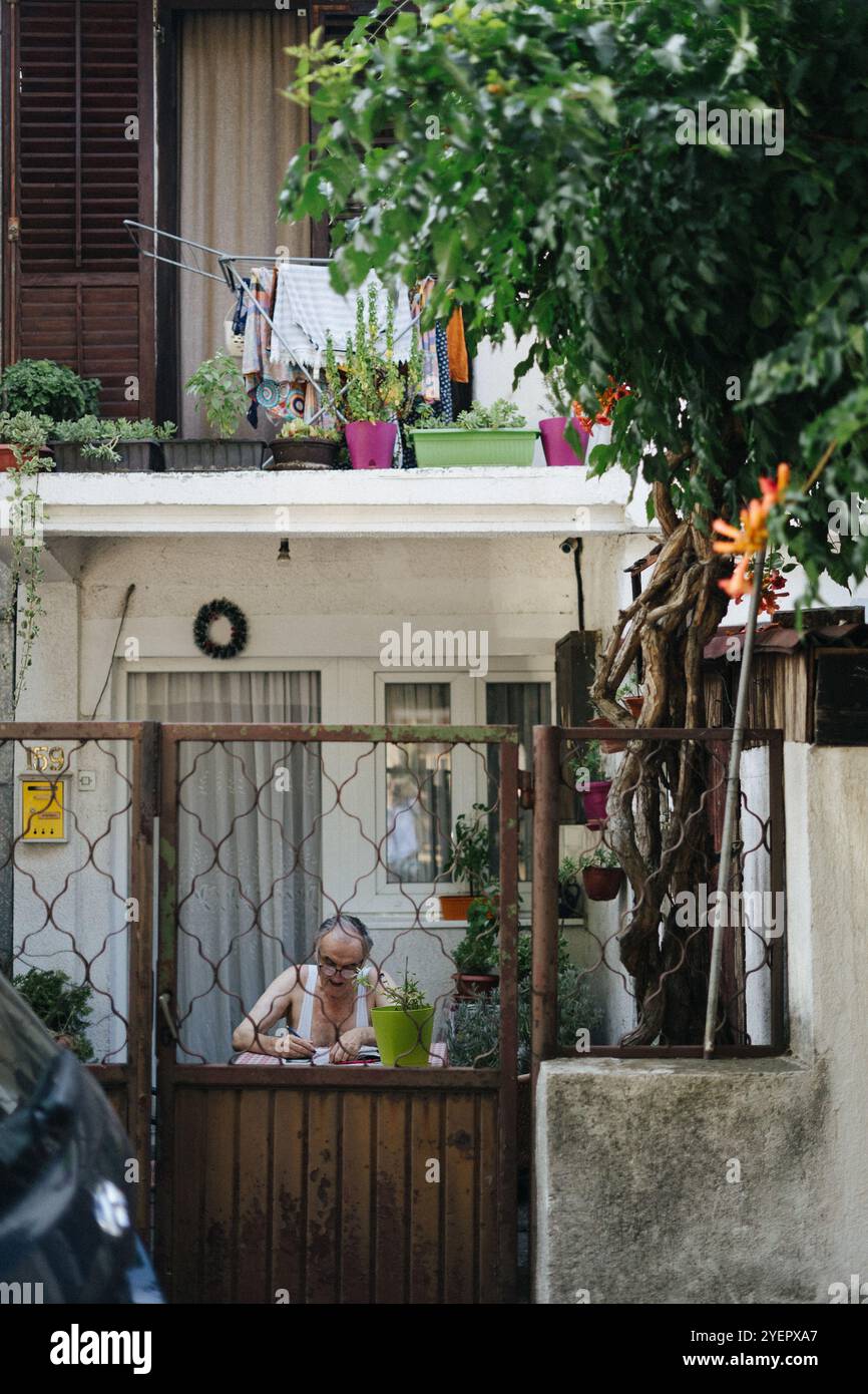 Ein älterer Mann schreibt Notizen in seinem Garten in Belgrad, Vo Stockfoto Ein älterer Mann schreibt Notizen in seinem Garten in Belgrad, Vo Stockfoto