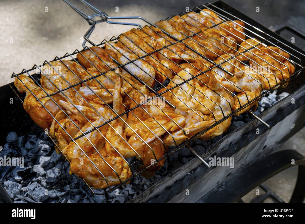 BBQ Picknick Zeit geröstete Hähnchenschenkel und Flügel auf dem Grill. Grillfleisch auf Grillgitter im Freien leckeres Hühnersteak mit Rauchflammen, saftigem Fleisch Stockfoto