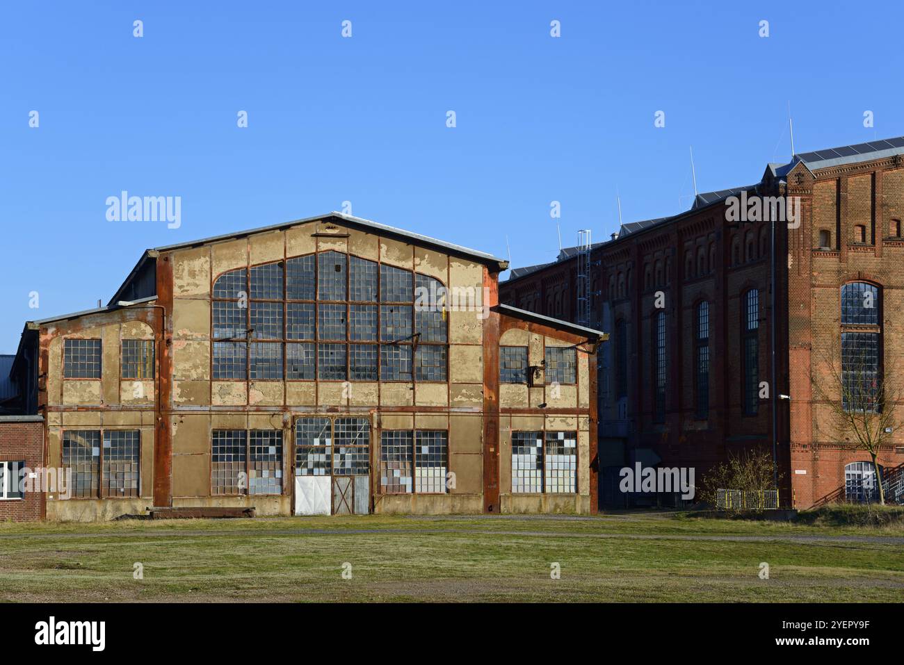 Verlassenes Industriebau mit großen Fenstern und Backsteinfassade unter blauem Himmel, Ilseder Huette, Ilsede, Peine, Niedersachsen, Deutschland, Eu Stockfoto
