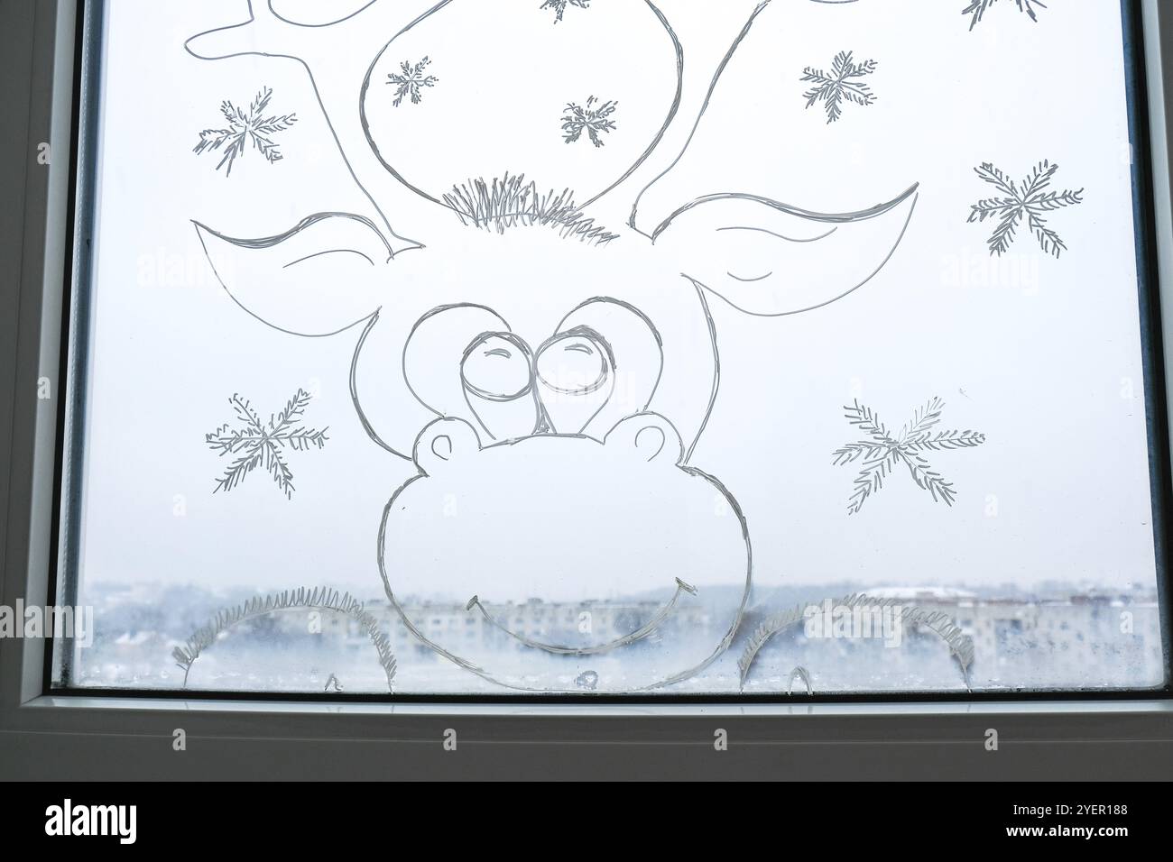 Weihnachtshirsch auf Fensterglas gemalt. Weihnachtliche Winterdekor auf dem Glasfenster. Weißes Muster von Hirsch. Schneekunst Tracery Fenster in der Weihnachtszeit. Stockfoto