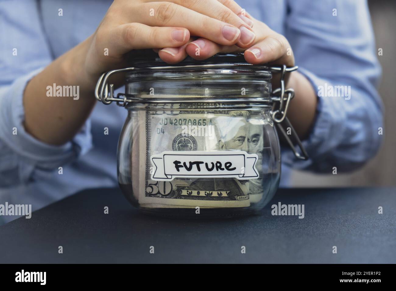 Weibliche Hände sparen Geld in einem Glas, gefüllt mit Dollarscheine. ZUKÜNFTIGE Transkription vor dem Glas. Verwaltung der persönlichen Finanzen zusätzliche Einnahmen für Stockfoto