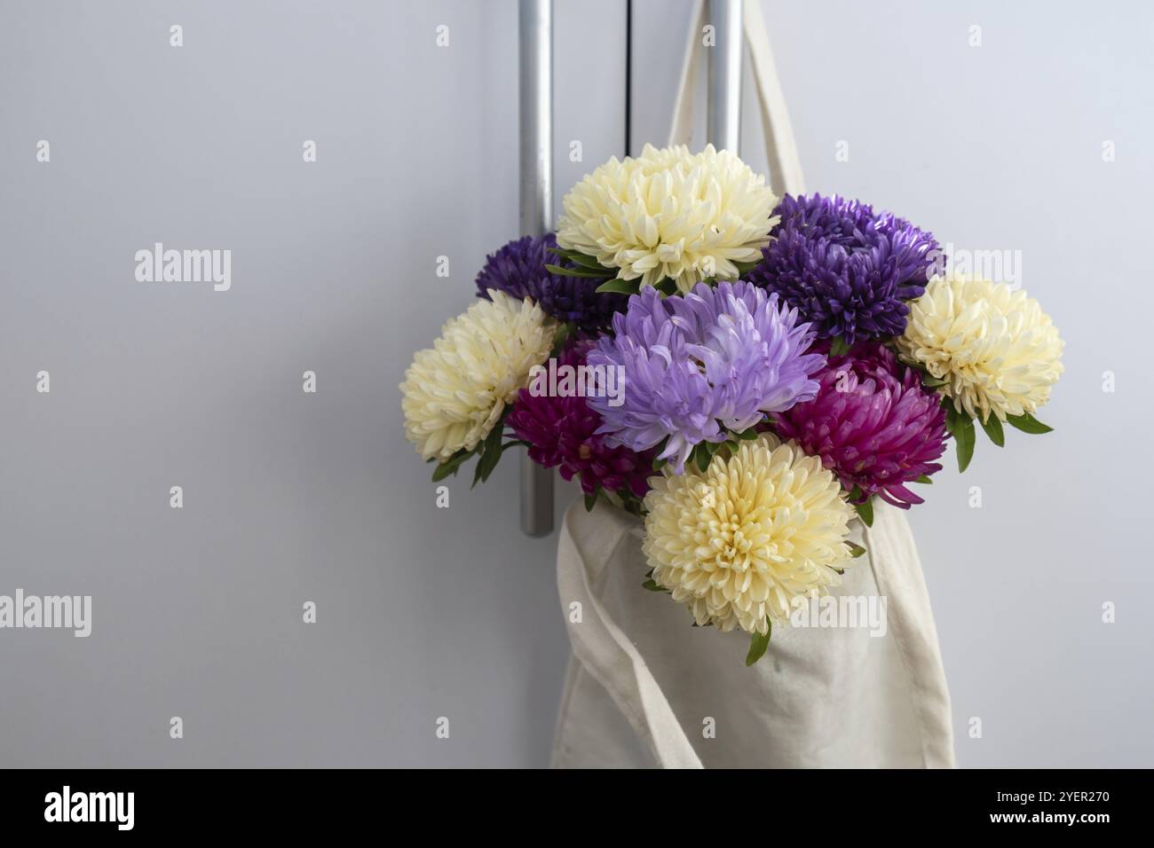 Blumenstrauß in Baumwoll-Naturbeutel zur Lieferung. Kopierbereich für Text. Konzept des Gratulationsgeschenks oder -Geschenks. Minimalistischer Frühling Stockfoto